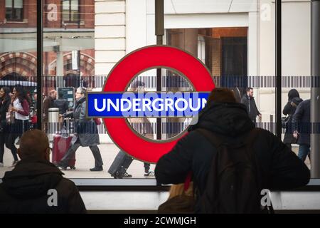 London, UK - February 2, 2020 - London underground sign at King's Cross St Pancras tube station with passing tourists Stock Photo