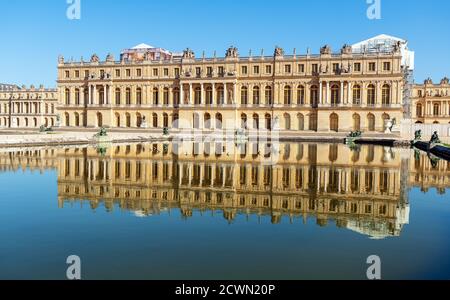 Reflection of Versailles palace facade in a pond at golden hour - France Stock Photo