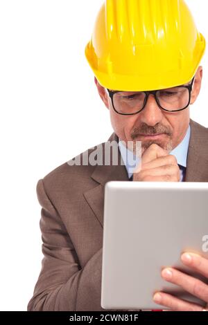 thoughtful construction engineer reading on his tablet pad on white background Stock Photo
