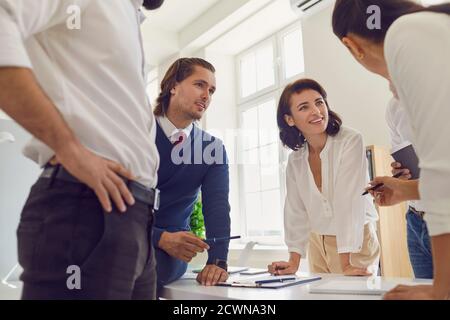 Young start-up team members talking and sharing ideas while working on business project together Stock Photo