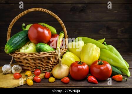Composition with various fresh vegetables and wicker basket on a wooden table. Stock Photo