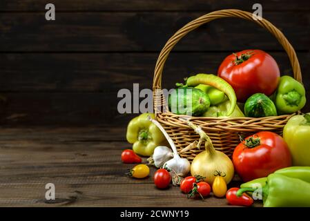 Composition with various fresh vegetables and wicker basket on a wooden table with copy space for text. Stock Photo