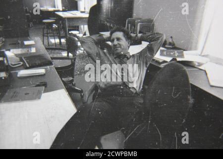 Fine 1970s vintage black and white photography of a funny professional man working on the job at the office. Stock Photo