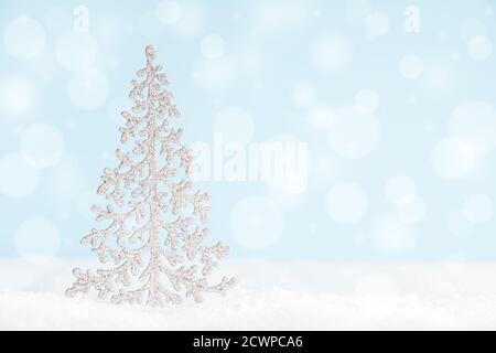 Christmas tree on surface with snow and defocused lights with copy space. Stock Photo