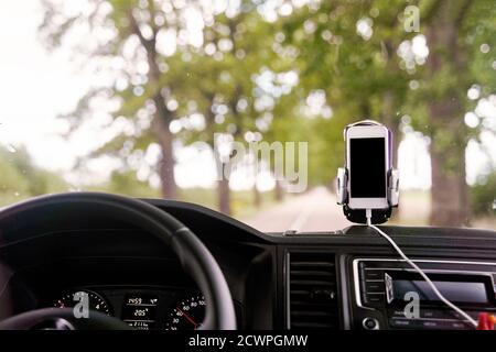 Mobile phone with GPS card in the car. A white smartphone on a stand in the car is used for navigation. Stock Photo