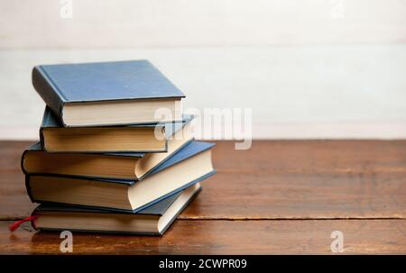 stack of blue books on old wooden shelf with dark background Stock Photo