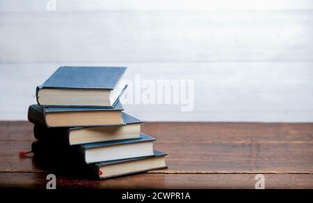 stack of blue books on old wooden shelf with dark background Stock Photo