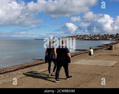 slim woman and obese man walking at sea front in hampton-on-sea coast in east kent uk september 2020 Stock Photo