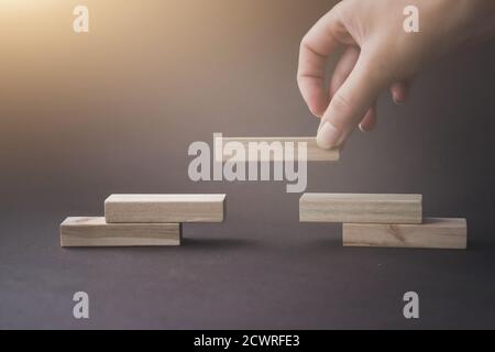Wooden blocks stacking as a pyramid staircase on brown background. Business organization startup concept Stock Photo