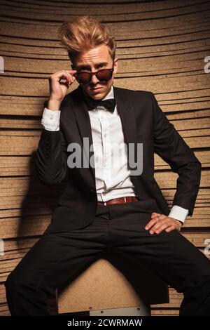 Elegant blond business man sitting while taking off his sunglasses. Stock Photo