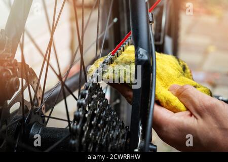 bicycle maintenance and repair - cleaning and oiling mountain bike chain and gear with oil spray Stock Photo