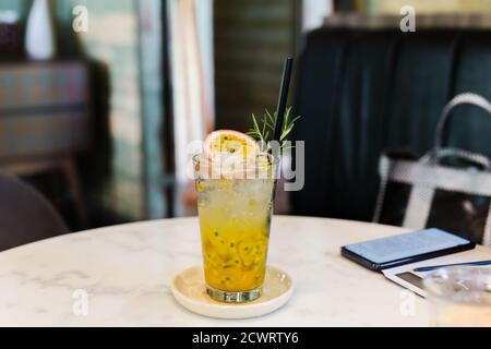 Fresh passion fruit juice in glass with green leaf and cell phone on table. Stock Photo