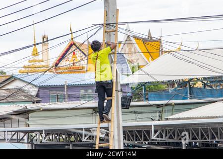 SAMUT PRAKAN, THAILAND, JUN 15 2020, A worker on ladder did maintenance of solar panels mounted on a pole on a street. Stock Photo