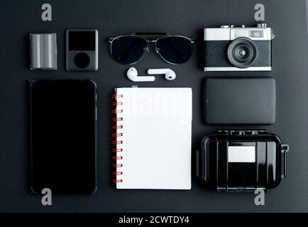 Top view of workspace photographer with old photo camera, headphones, PDA, waterproof case, white paper, camera battery. mp3, sunglasses, hard drive. Stock Photo