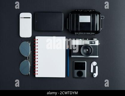 Top view workspace photographer with, white portable wifi, blue sunglasses, black hard drive, white notebook, waterproof case, old photo camera, gray Stock Photo