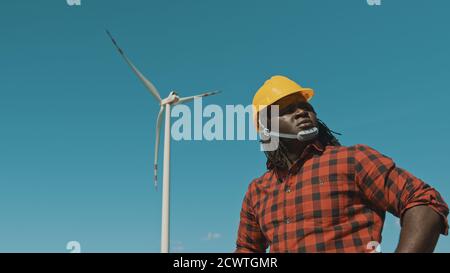Young engineer african man with yellow helmet working in wind turbine farm . High quality photo Stock Photo