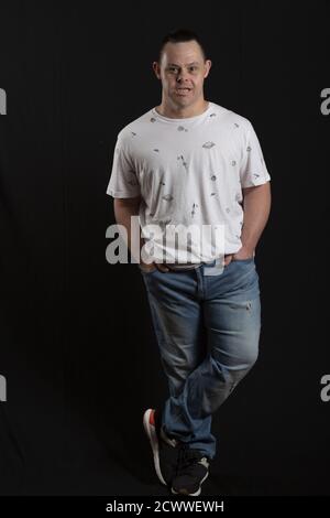 Happy man with down syndrome in the photo studio on black background Stock Photo