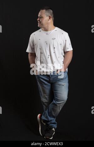 Happy man with down syndrome in the photo studio on black background Stock Photo