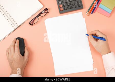Man's hands working with pc computer and calculator, notebook, pen, mouse, computer on modern pink desk table at office. financial reports,resume, bri Stock Photo