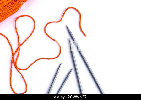 Knitting needles and orange wool on white background. Stock Photo