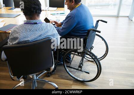 Businessman in wheelchair using smart phone in conference room meeting Stock Photo