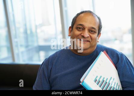 Portrait confident businessman with paperwork in office Stock Photo