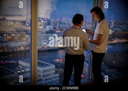 Businessmen with digital tablet working late at highrise office window Stock Photo