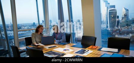 Business people working at laptop in highrise conference room meeting Stock Photo