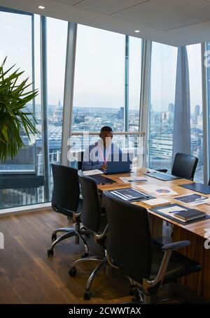 Businessman working at laptop in highrise conference room Stock Photo