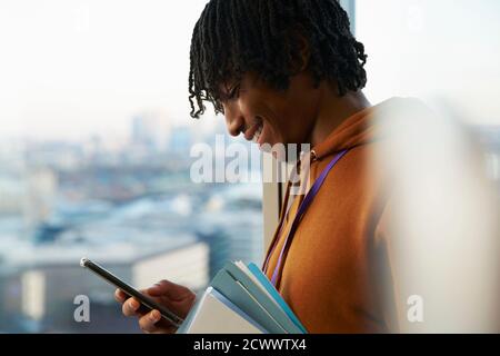 Smiling businessman using smart phone at window Stock Photo