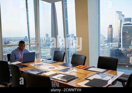 Businessman working at laptop in highrise conference room, London, UK Stock Photo