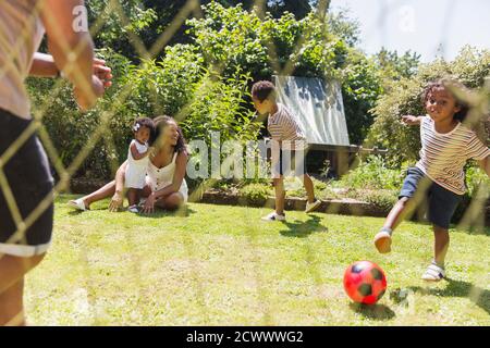 Happy family playing soccer in sunny summer backyard Stock Photo