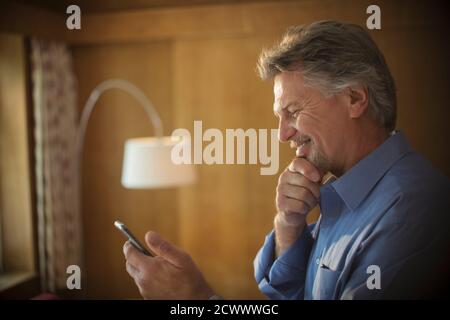 Smiling senior man using smart phone at home Stock Photo