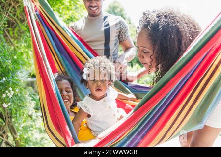 Portrait cute toddler girl in sunny summer hammock with family Stock Photo