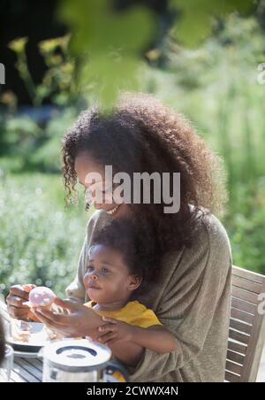 Mother and toddler daughter eating at sunny summer patio Stock Photo