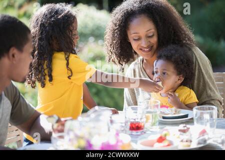 Family eating lunch at sunny summer patio table Stock Photo