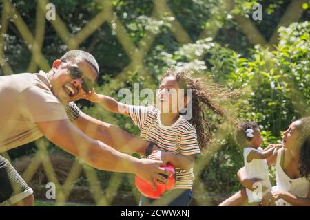 Playful family playing soccer in sunny summer backyard Stock Photo