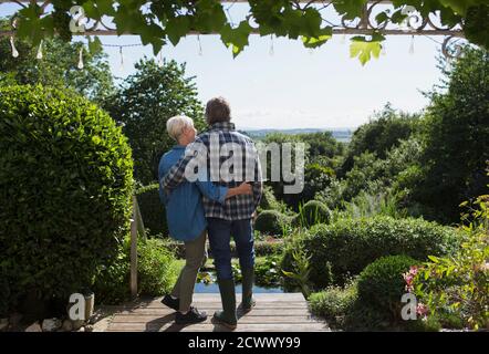 Affectionate senior couple hugging on sunny summer garden patio Stock Photo