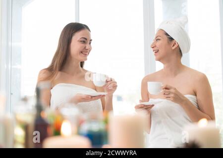 Two women drinking tea or herbal drinks while having conversation in luxury day spa. Wellness, leisure and healthcare concept. Stock Photo