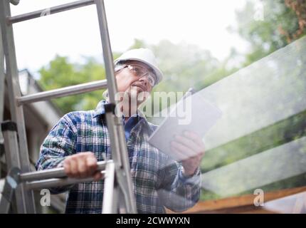 Senior male construction foreman using digital tablet on ladder Stock Photo