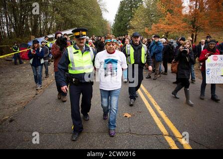 A protester is led away from a demonstration after being detained by Royal Canadian Mounted Police (RCMP) officers during a demonstration against the proposed Kinder Morgan pipeline protest on Burnaby Mountain in Burnaby, British Columbia November 20, 2014. Environmental protesters have been blocking work at two Kinder Morgan Energy Partners LP sites in the Vancouver suburb of Burnaby, three days after a court injunction for their removal came into effect. Kinder Morgan, which hopes to triple the size of its 300,000-barrel-per-day Trans Mountain pipeline, plans to bore two holes deep into Burn