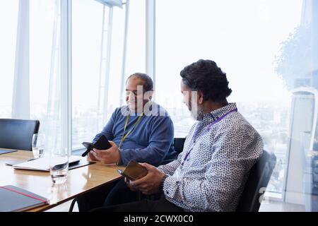 Businessmen using smart phones in conference room meeting Stock Photo