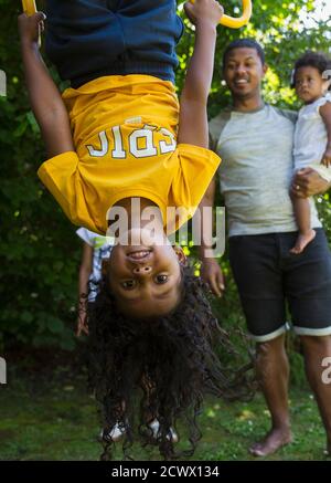 Portrait playful girl hanging upside down Stock Photo