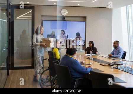 Businesswoman bringing lunch to colleagues in conference room meeting Stock Photo