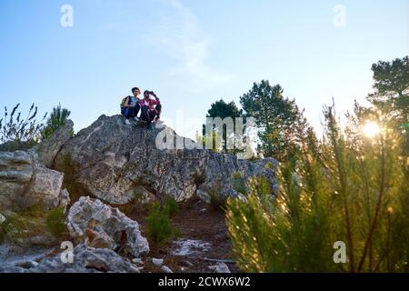 Young hiking couple relaxing on rock in sunny nature Stock Photo