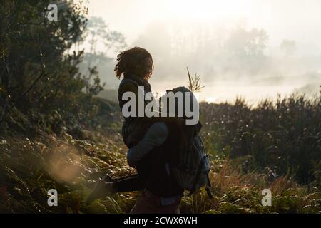 Silhouette affectionate young couple hiking in nature Stock Photo