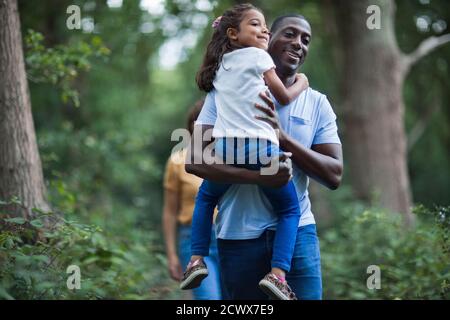 Happy father carrying daughter on hike in woods Stock Photo