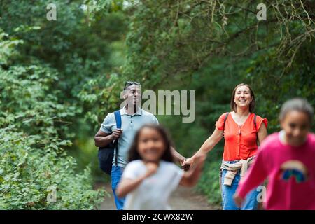 Happy family hiking on trail in woods Stock Photo