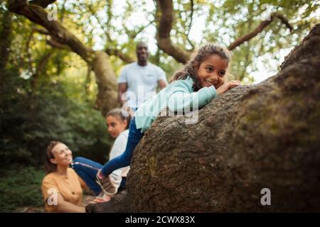 Happy family climbing tree in woods Stock Photo