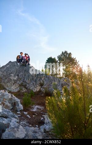 Young couple with binoculars on rock in nature Stock Photo